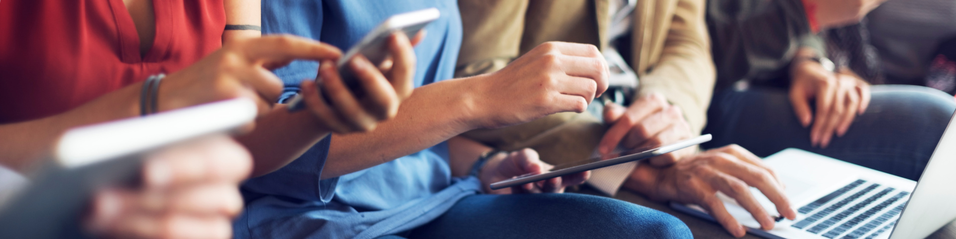 Mehrere Personen nutzen gemeinsam Smartphone, Tablet und Laptop.